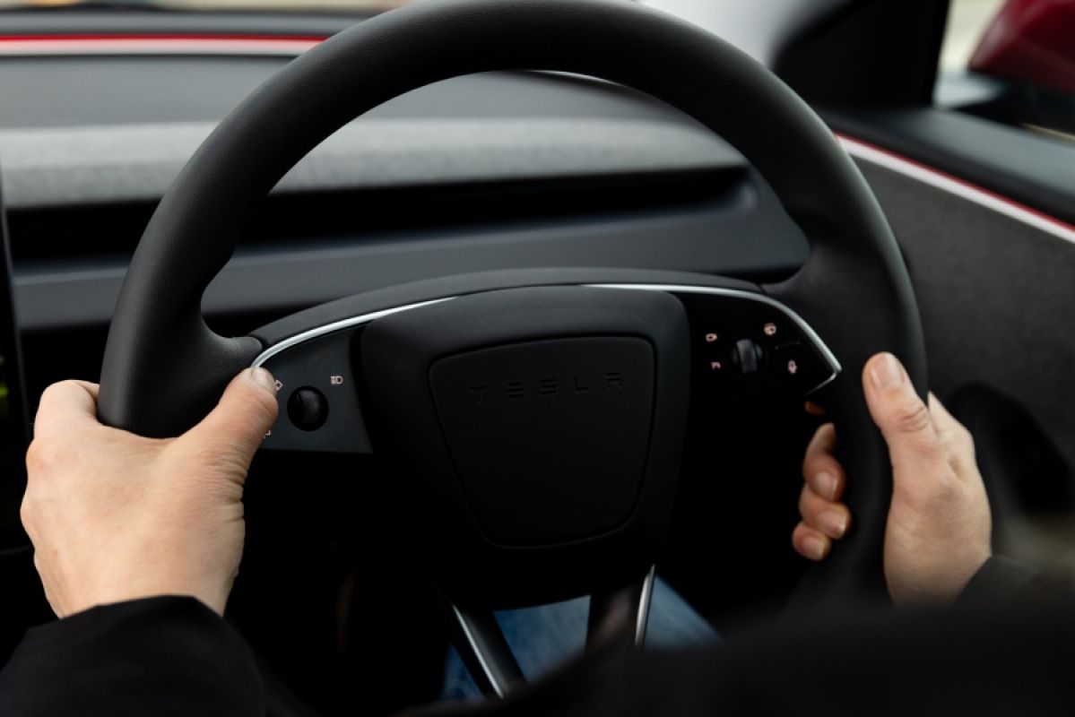 Two hands holding the Tesla Model 3 steering wheel firmly
