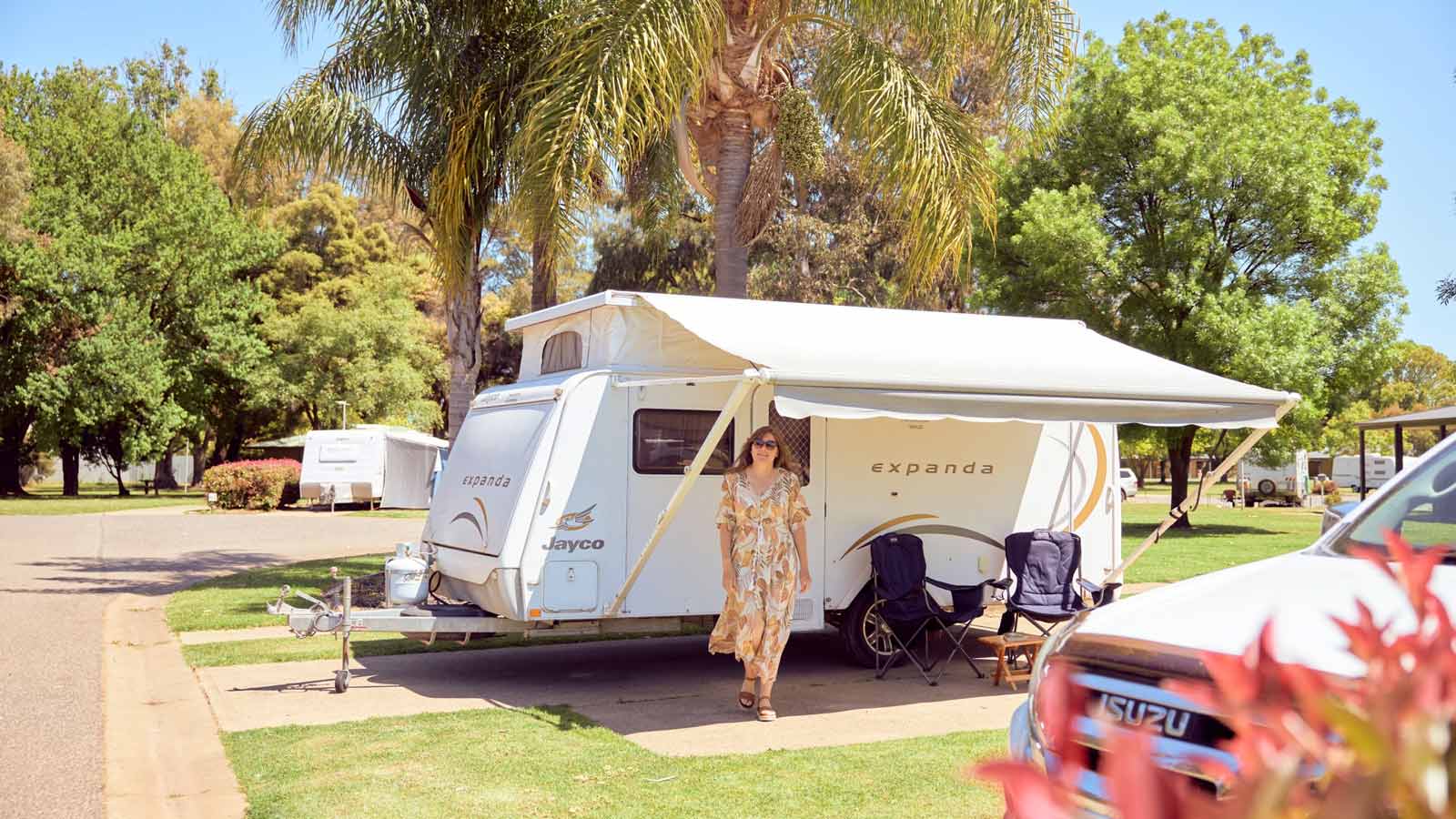 Woman standing next to her caravan on a sunny day