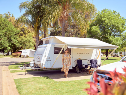 Woman standing in front of her caravan on a sunny day