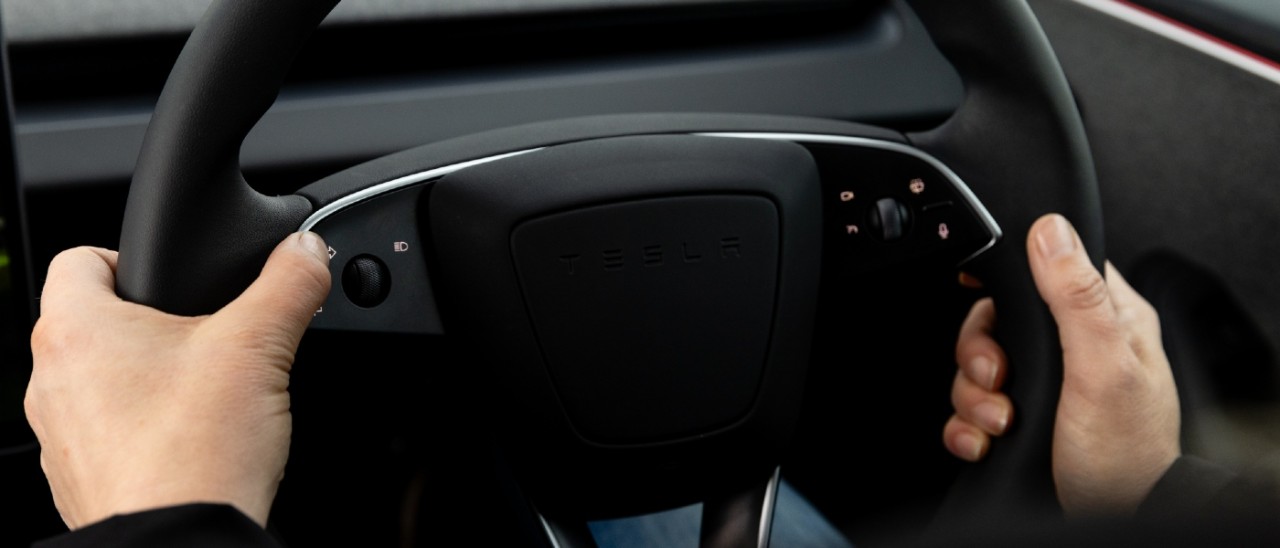Two hands holding the Tesla Model 3 steering wheel firmly