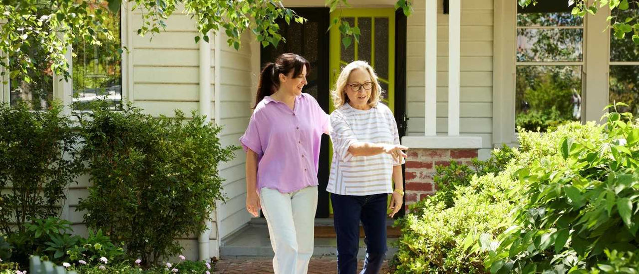 Two women walking together outside of a house