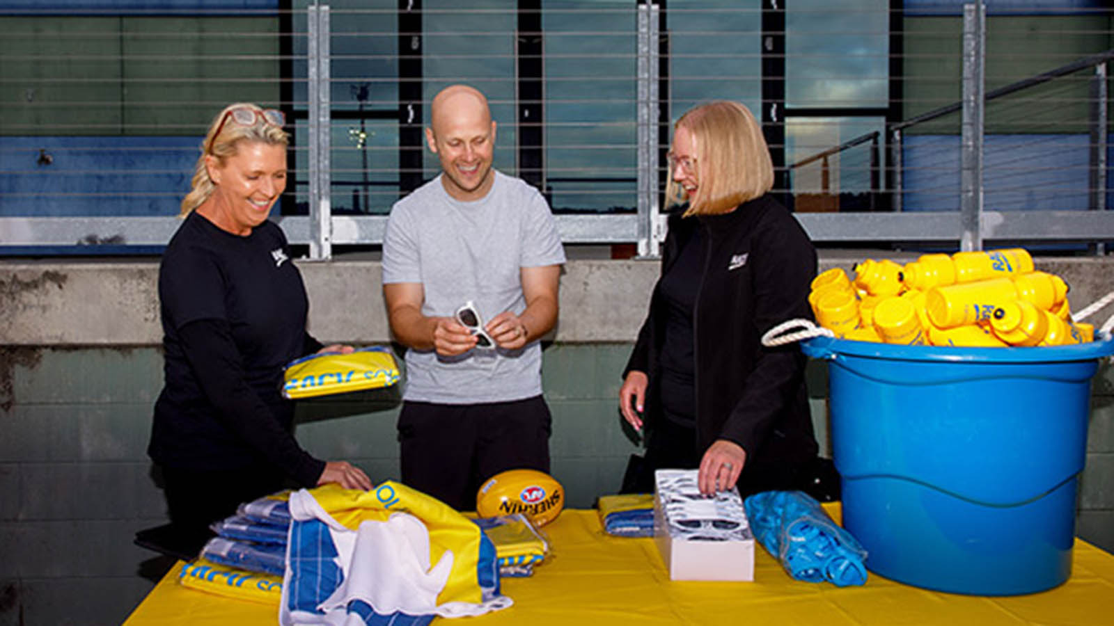 RACV employees and Gary Ablette smiling at a kids footy event.