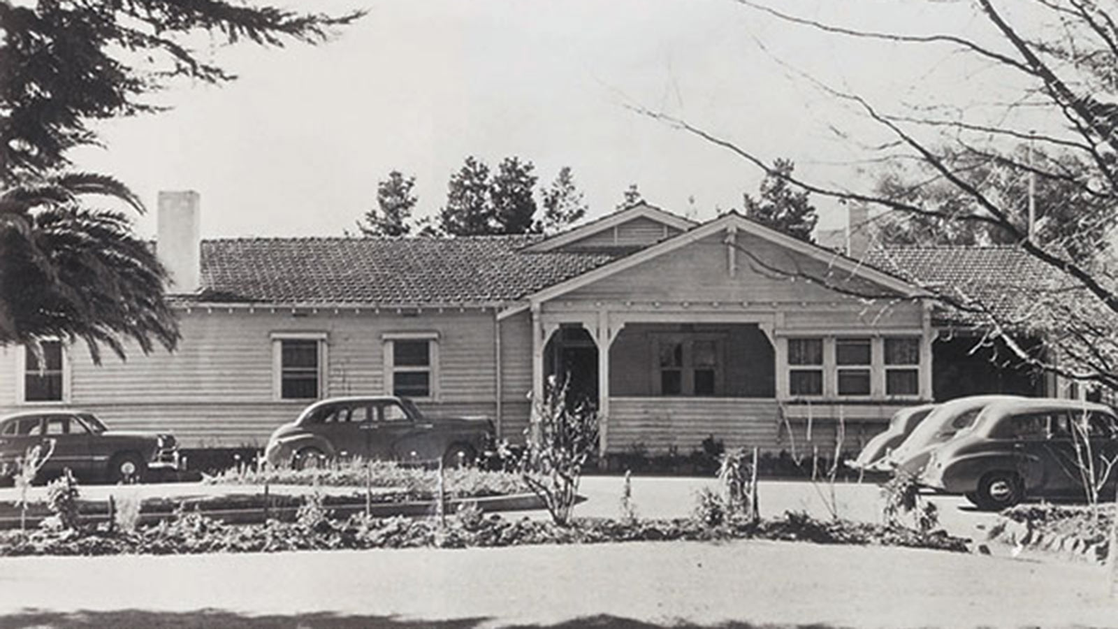 Heritage photo of RACV golf house in Healesville, with vintage cars parked at the front.
