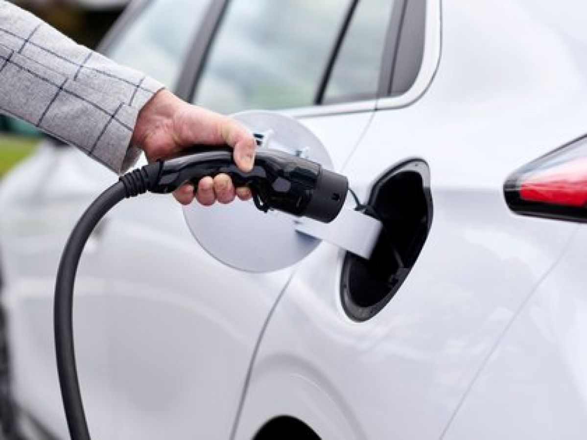 Motorist charging their white electric vehicle