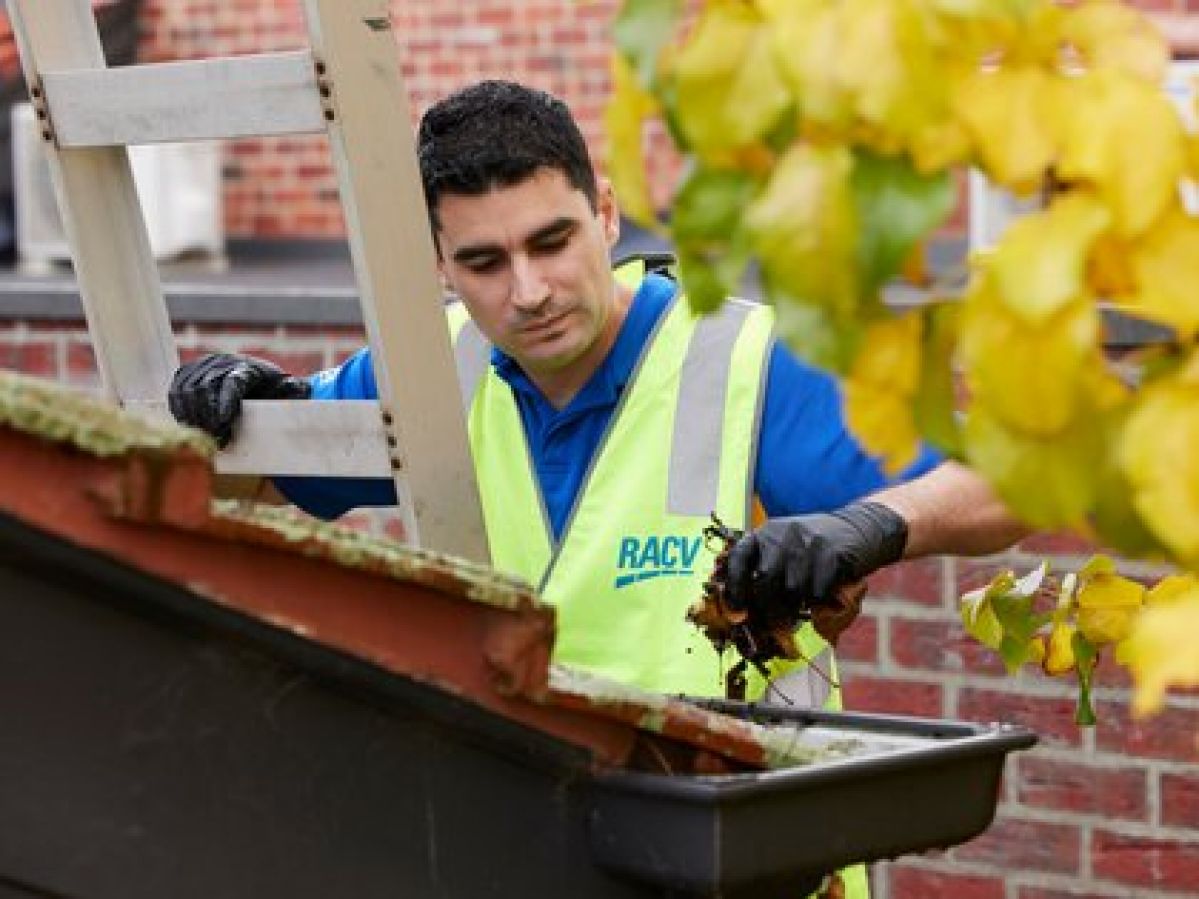 man on ladder cleaning gutters