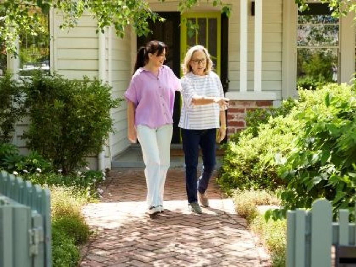 Two women talking outside of a house