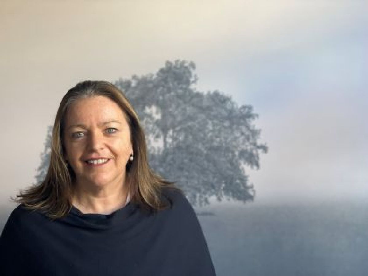 Kathryn Ryan standing in front of her landscape painting  of a tree