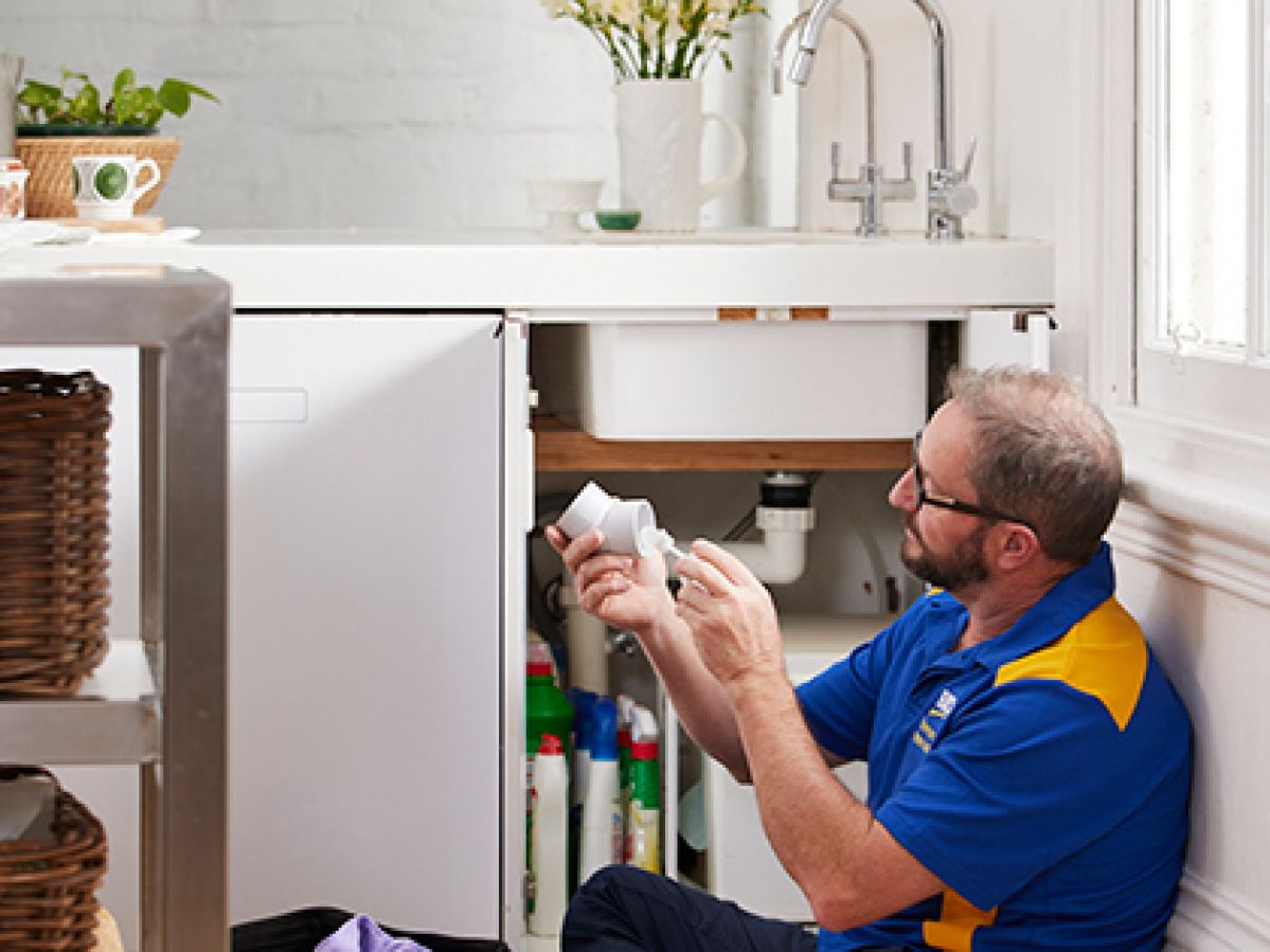 A man fixing a piece of pipe underneath a sink