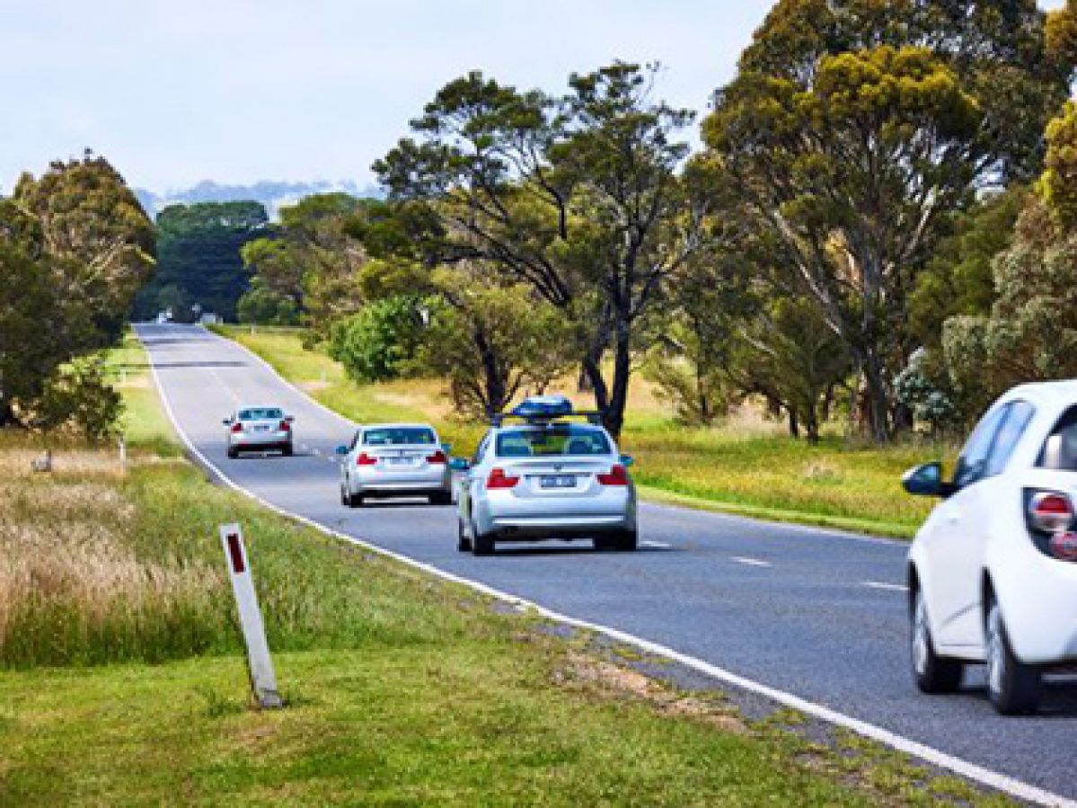 Four cars driving along a rural highway.