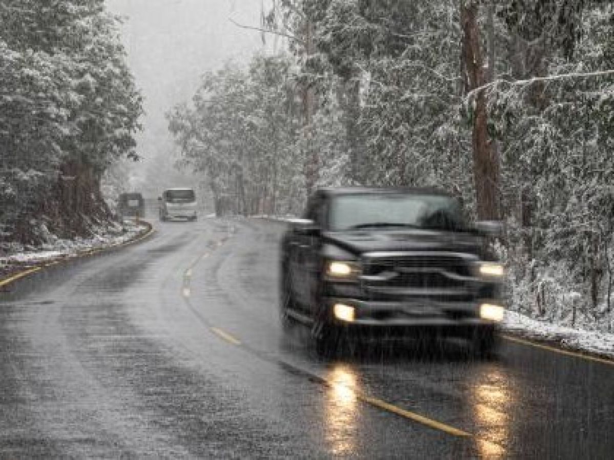 A black ute driving in rainy and snowy conditions