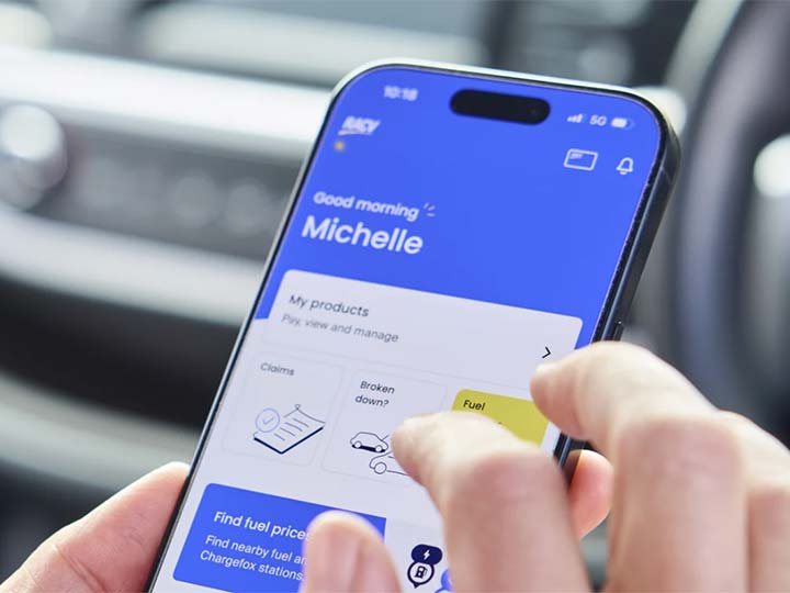 Finger clicking a button in the RACV App on a mobile phone.