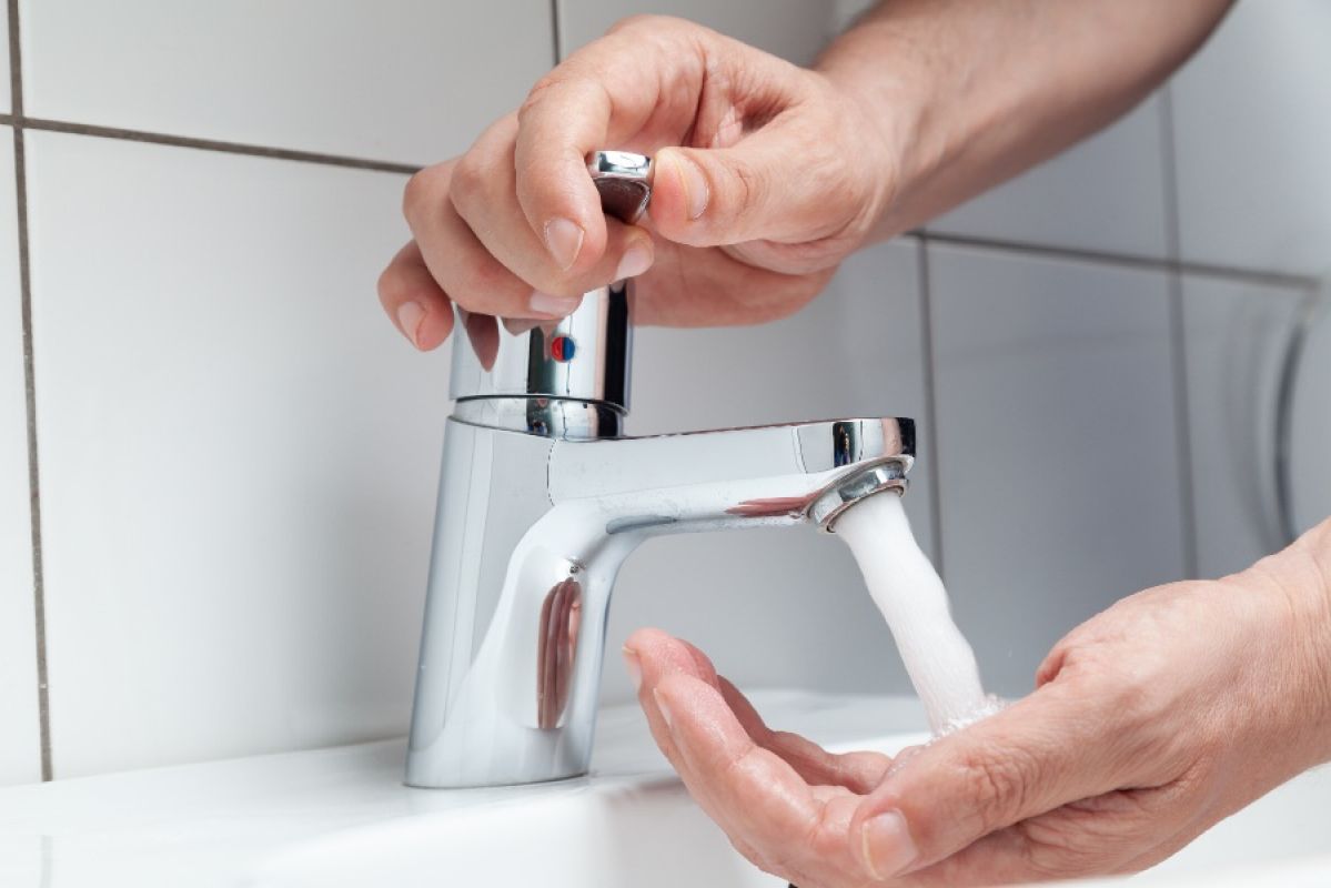man turning hot water tap on