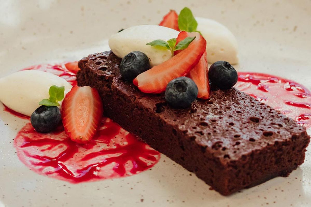 Chocolate cake served on white plate with fruit