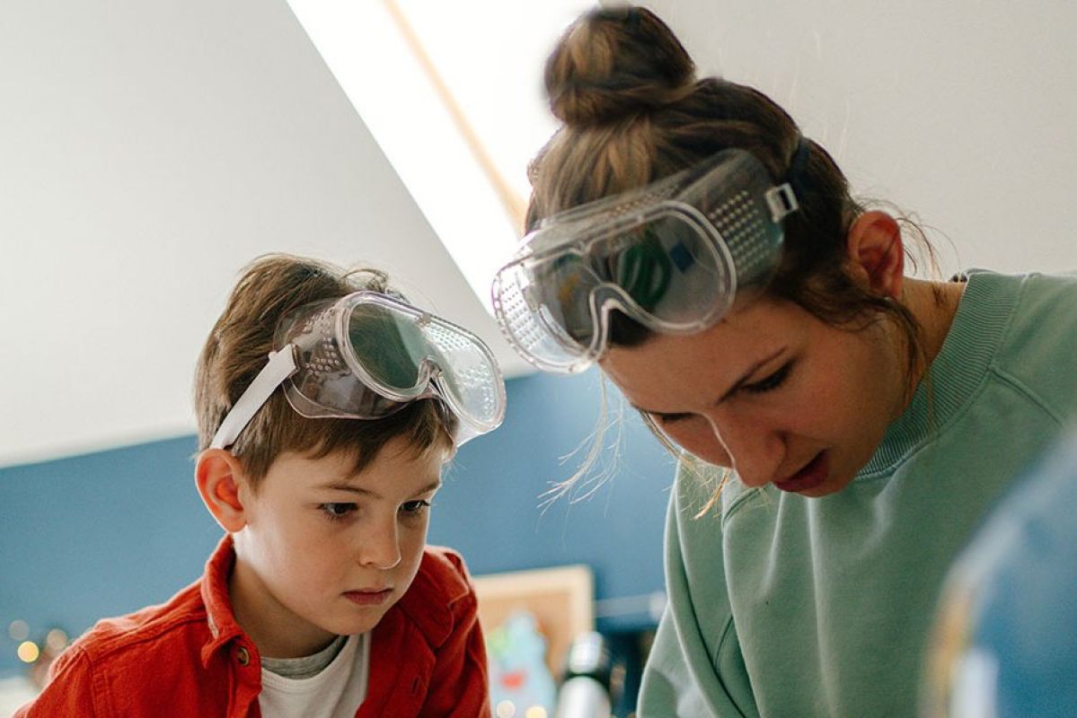 child and adult with safety googles in classroom doing science experiement