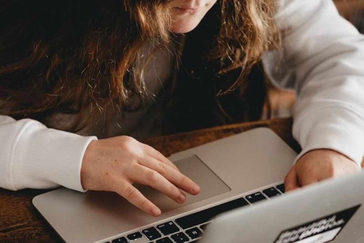 child with long hair working on a laptop