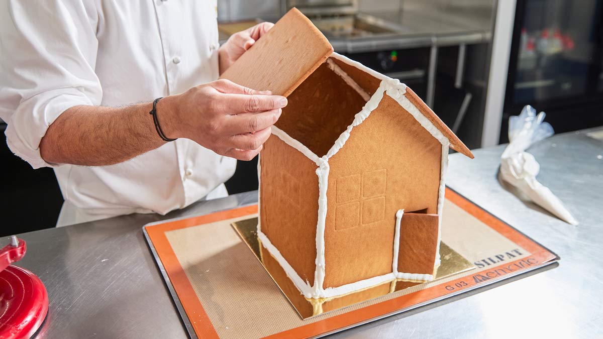 Chef building gingerbread house