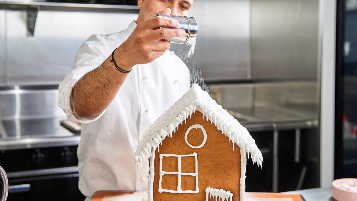 Chef decorating gingerbread house