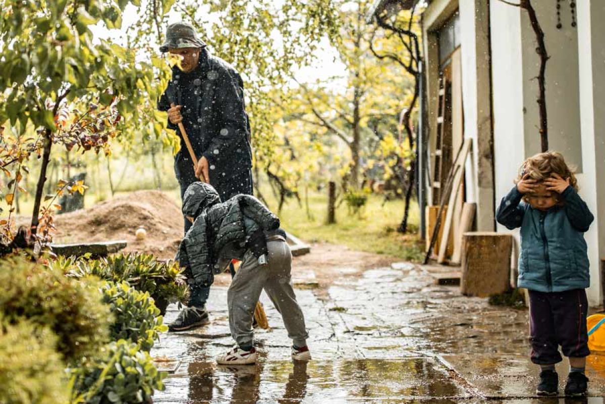 family together cleaning front house from water