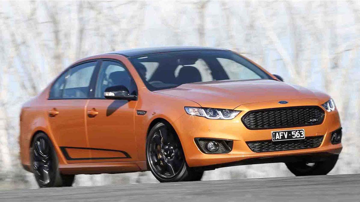 Orange Ford FG Falcon driving in front of trees