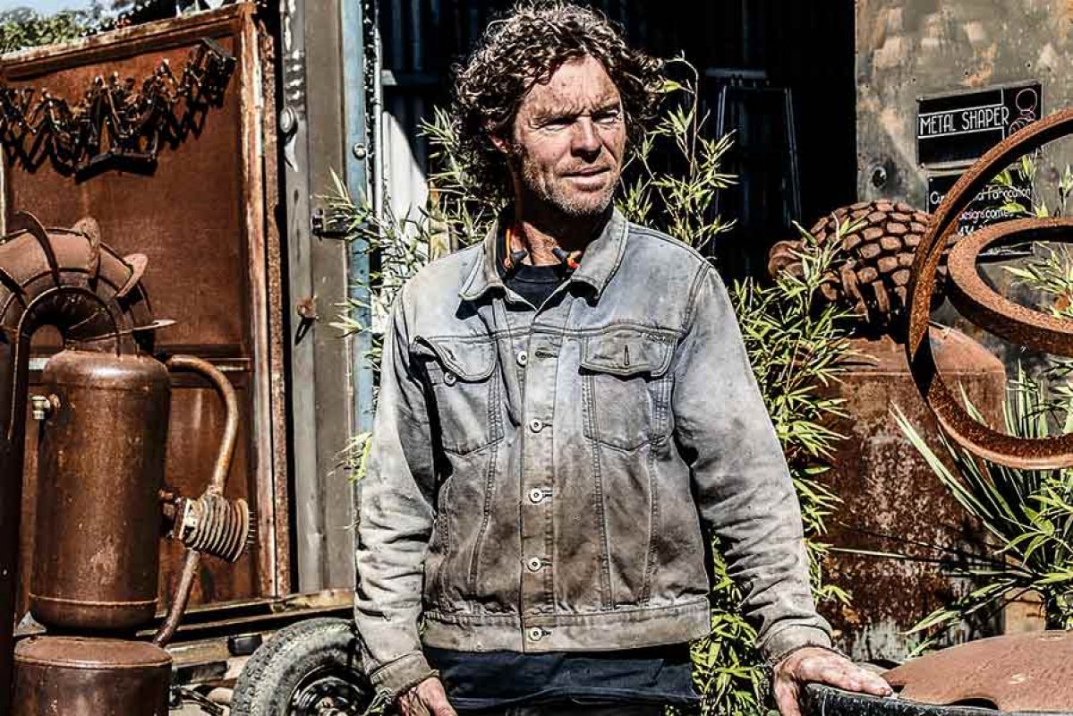Man standing up surrounded by rusty metal objects.