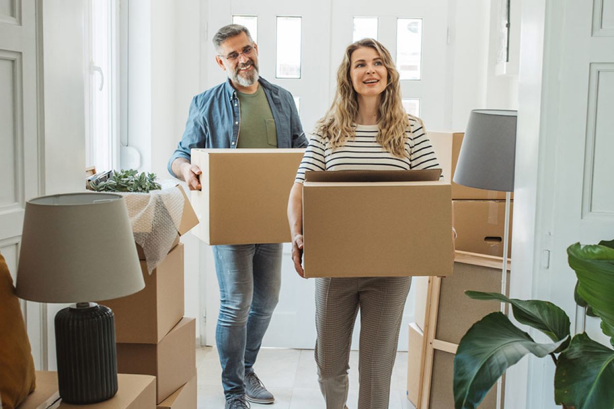 A man and woman moving boxes into a new home