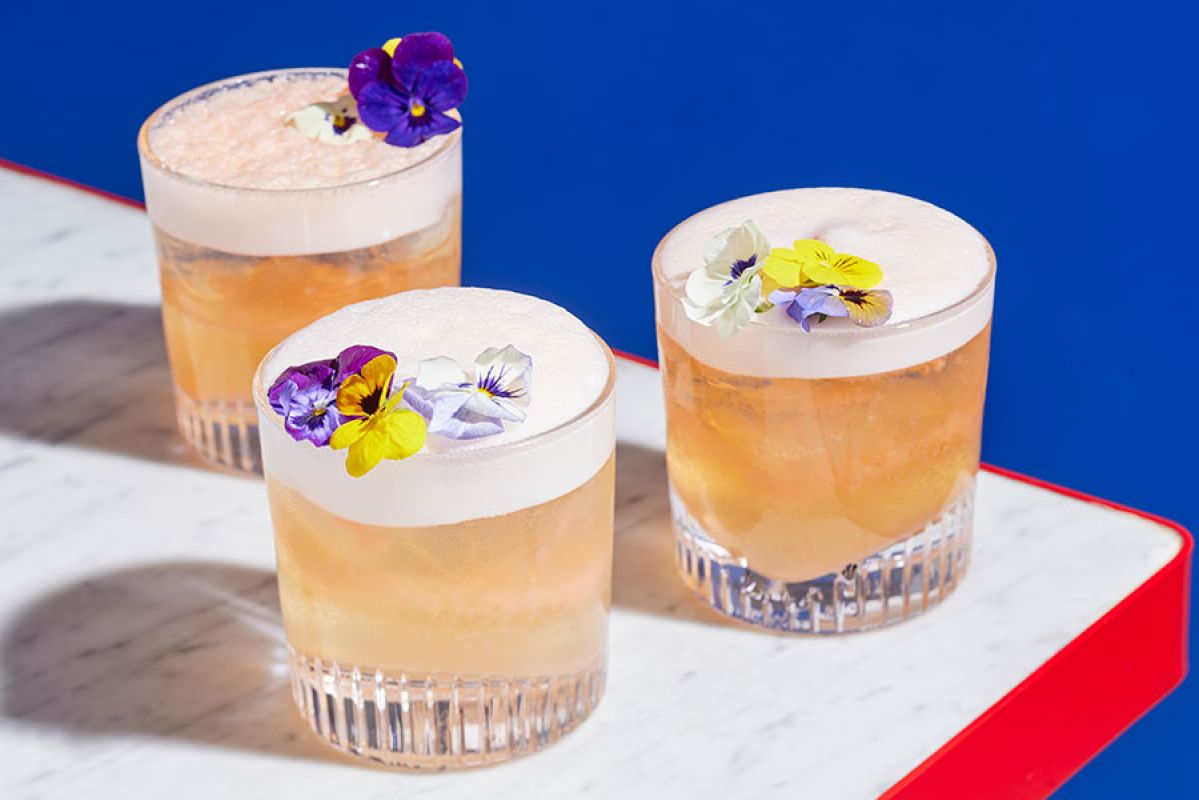 three cocktails lined up on the corner of a bench