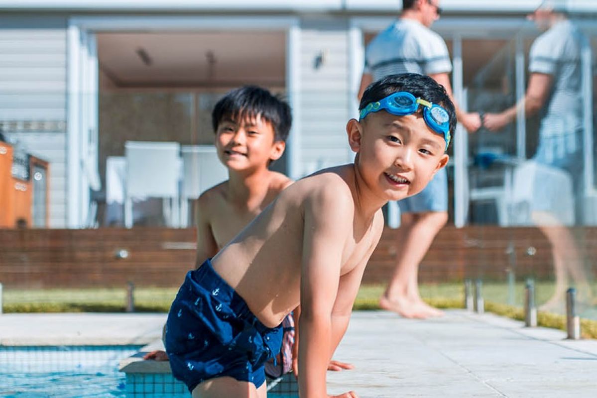two children climbing out of a swimming pool