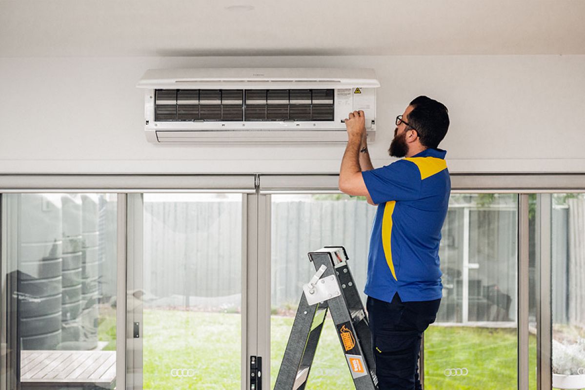 Tradesperson fixing a heater on a ladder
