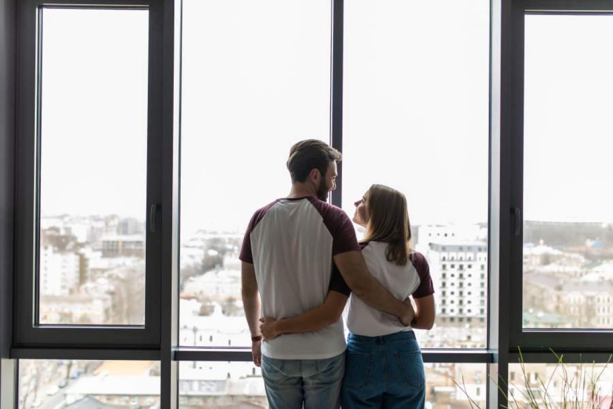 Couple looking out of their apartment window