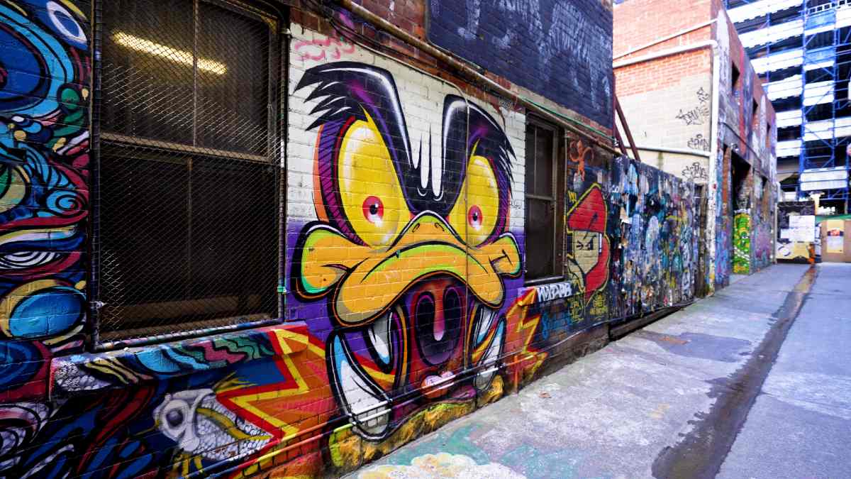 A Melbourne laneway with a mural of a duck-like cartoon monster painted on a wall