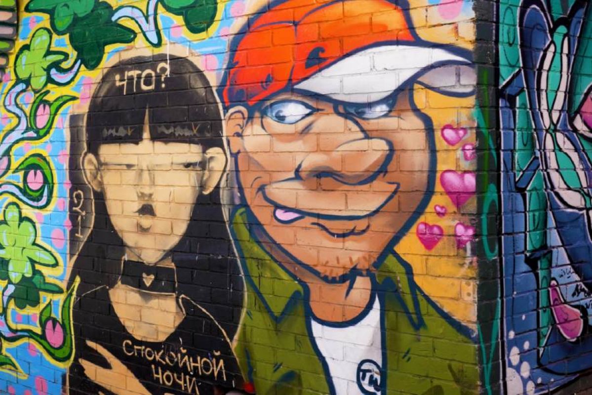 A colourful street art mural of a goth looking cartoon woman and a goofy looking man