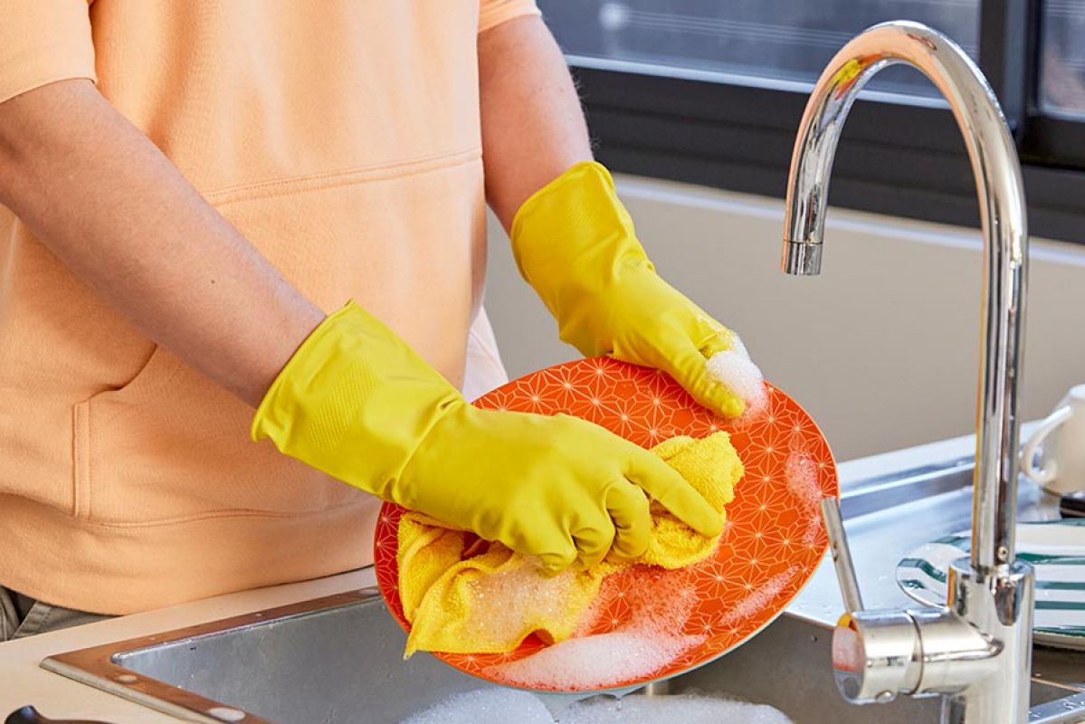 A person washing up dishes in a kitchen sink