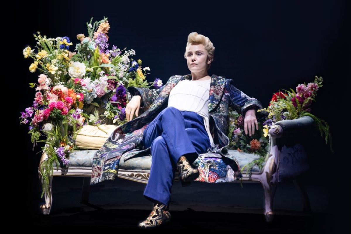Eryn Jean Norvill as Dorian Gray lounging on a divan covered in flowers
