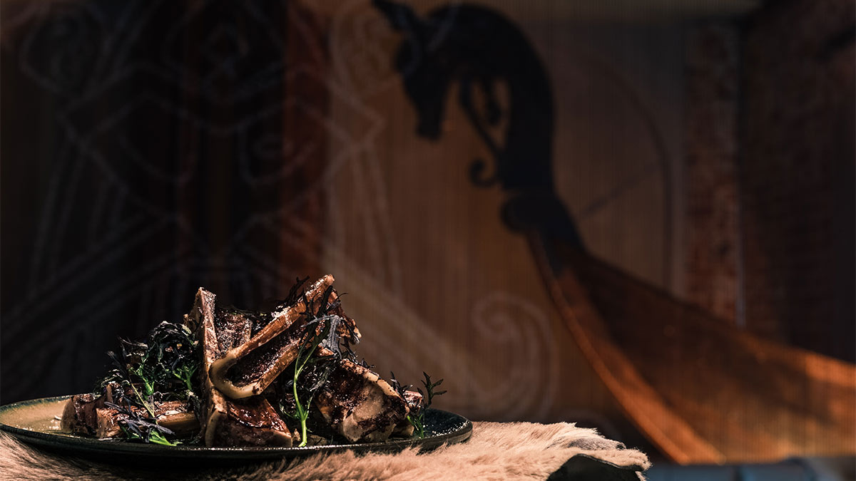 A plate of roasted bone marrow oon a white fur at Mjolner. A Viking longship replica is in the background