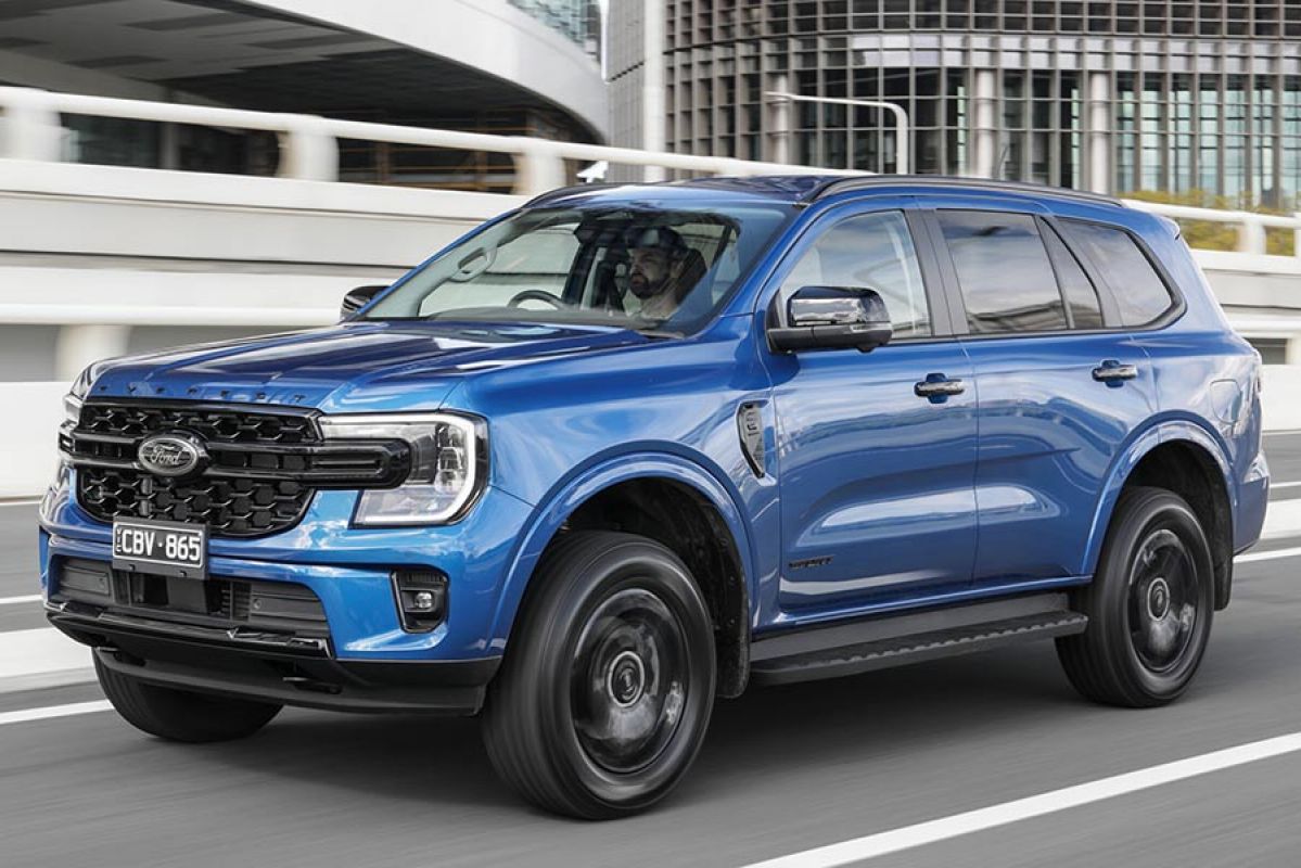 A blue Ford Everest Sport drives on the road.