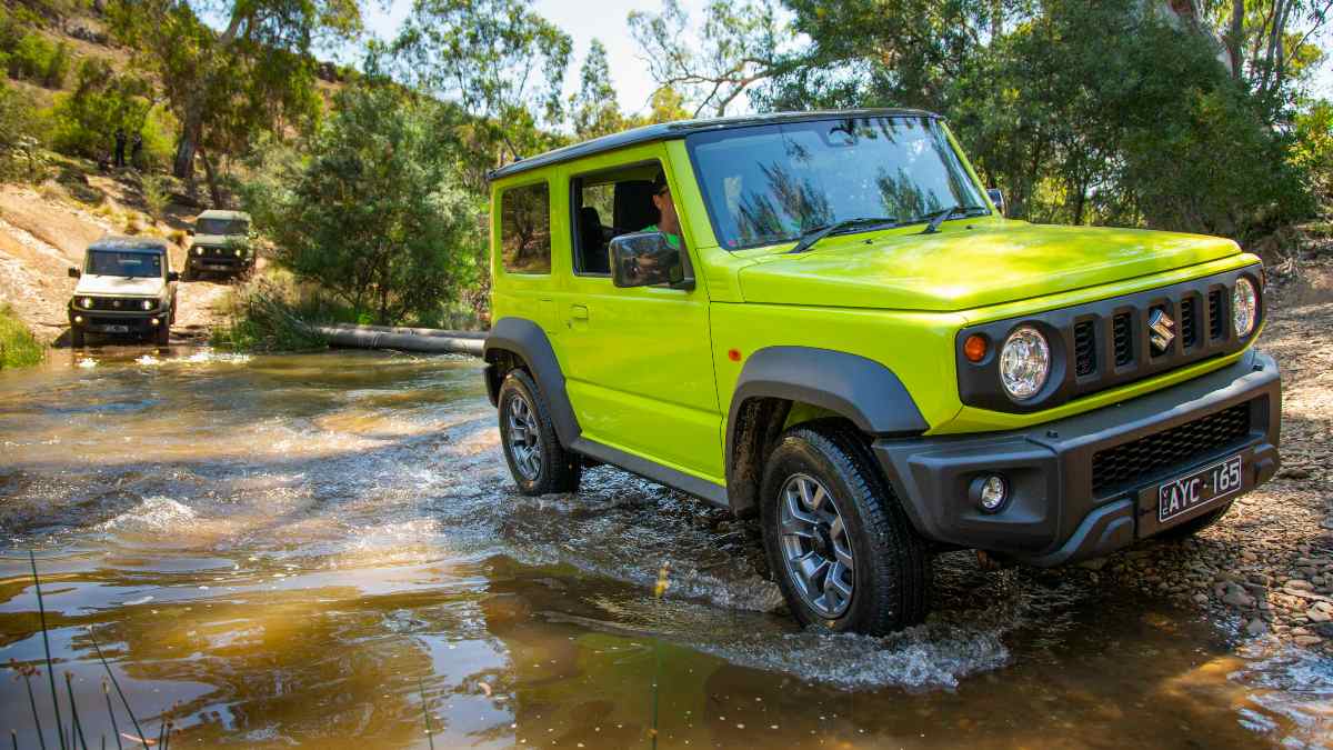 Fluro green Suzuki Jimny driving through a river bed
