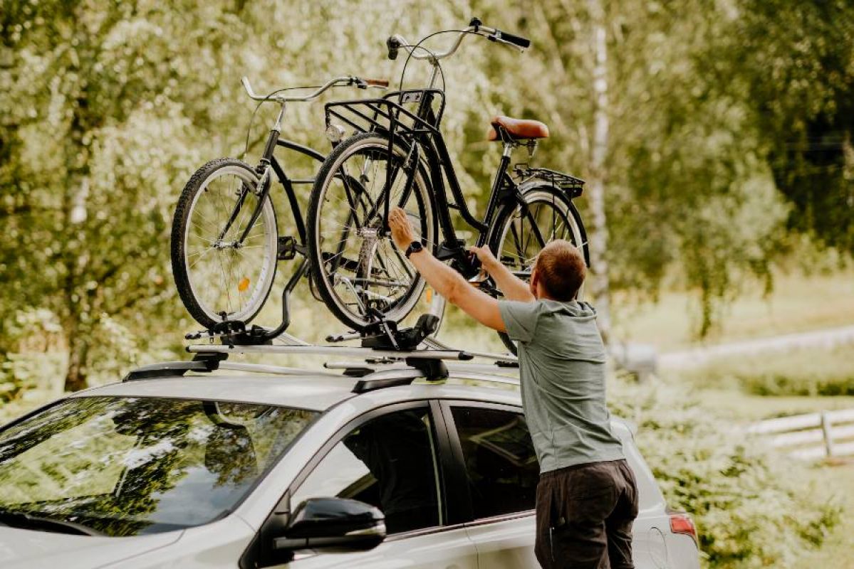 man putting bikes on car roof racks