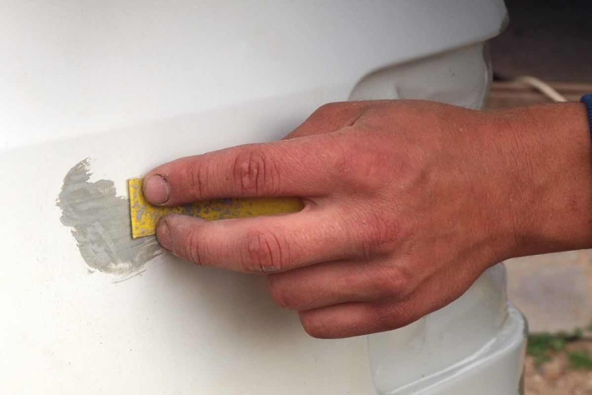 man sanding a car scratch