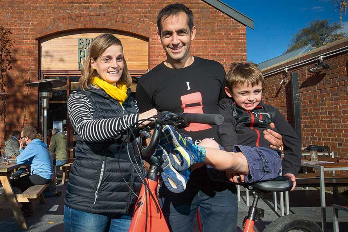 Family of three standing with bike and helmet