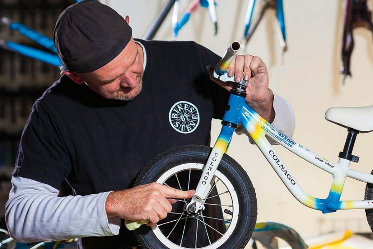 Man with small bike on tables fixing wheel.