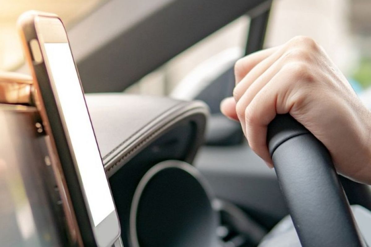 mounted smartphone in car next to hand on steering wheel