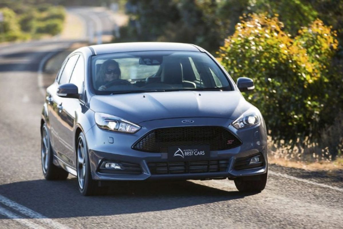gray ford focus driving on road next to bushes