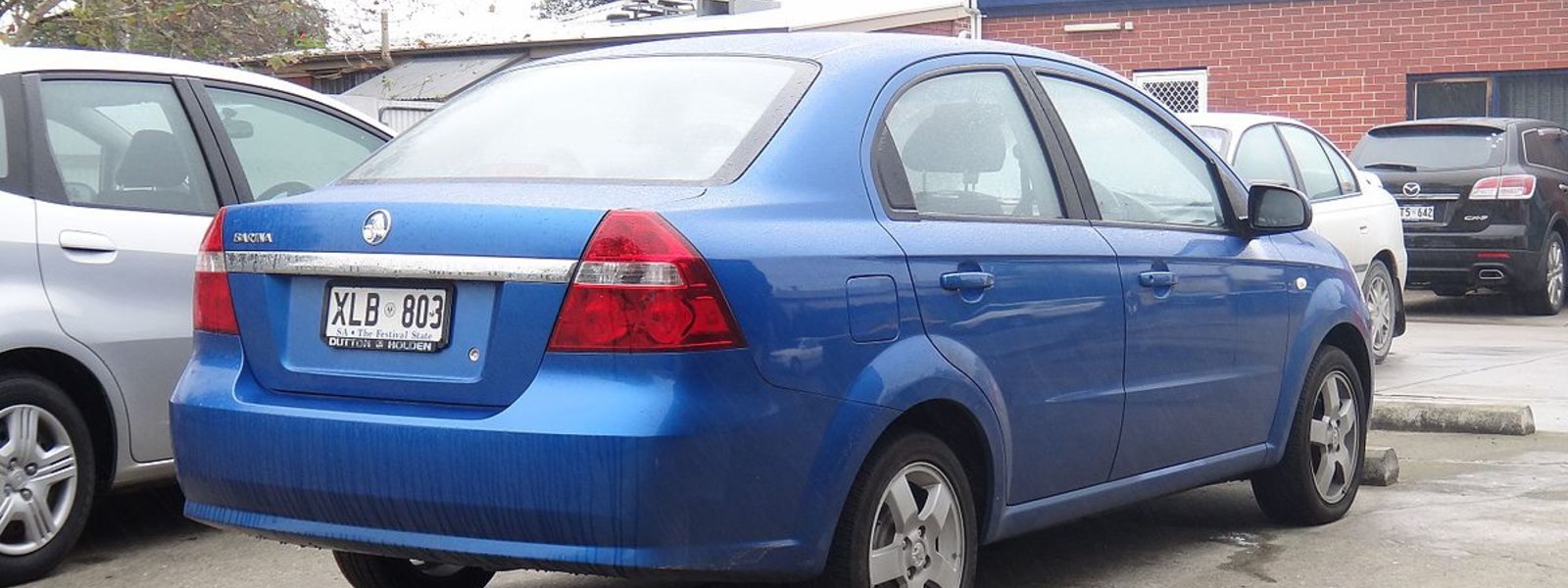 blue holden tkbarina parked in parking lot next to other silver car
