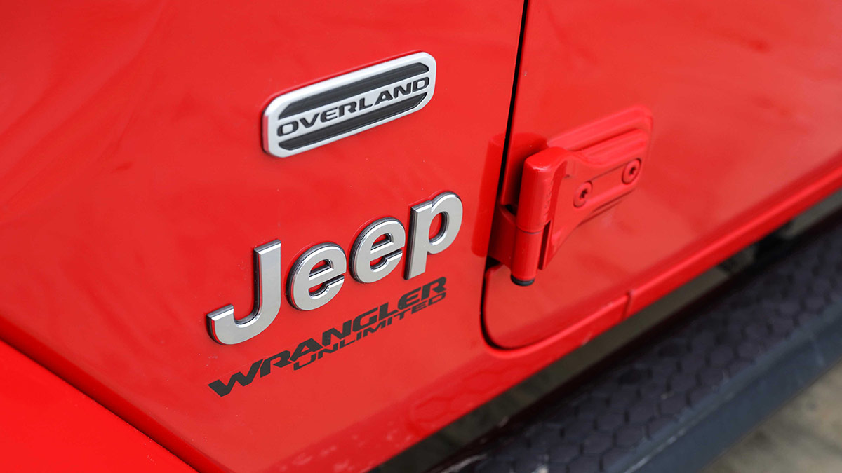 Close up of the Jeep badge on the side of a red Jeep Wrangler JL 2019 car
