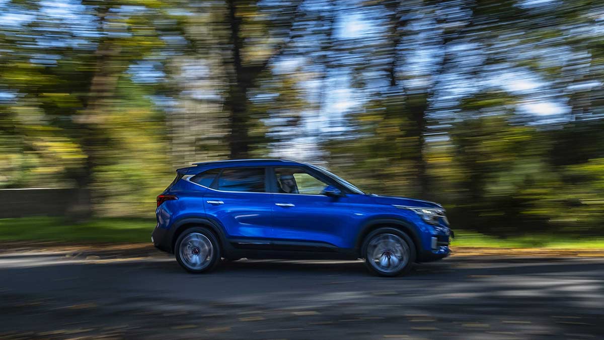 Side view of a blue Kia Seltos car in motion