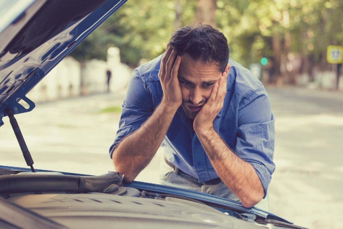 frustrated man looking at his car engine 