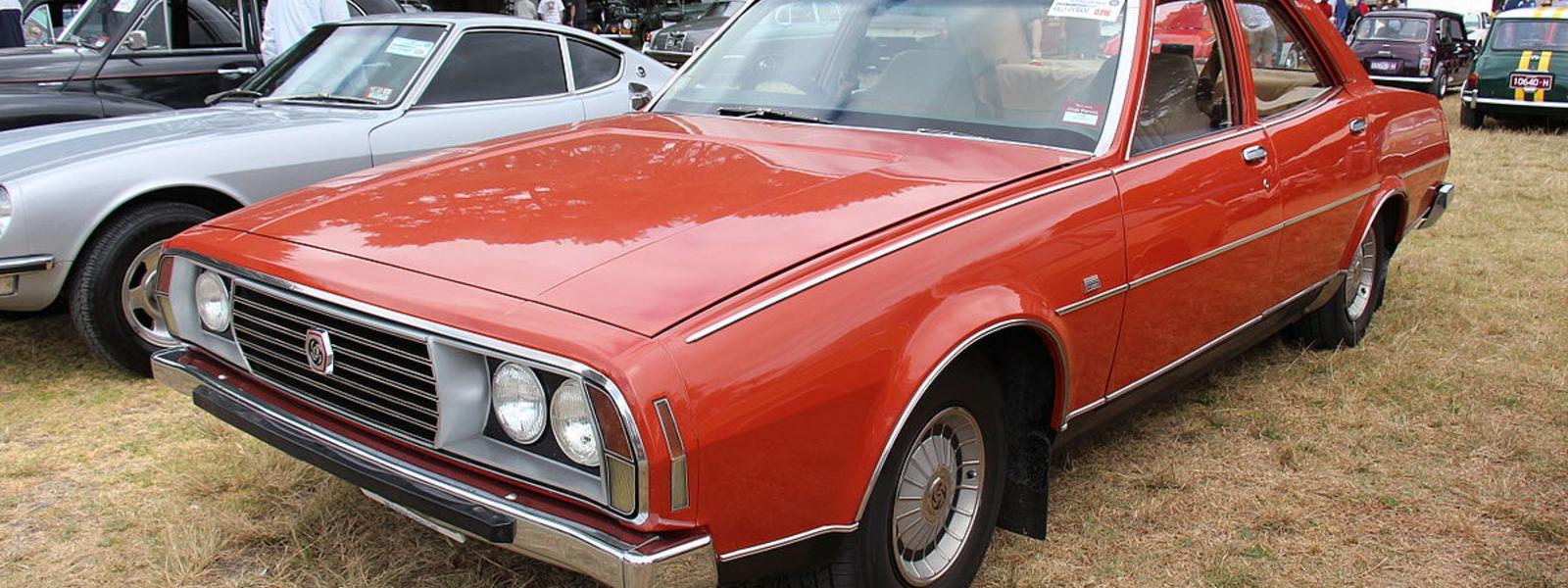blood orange leyland p76 parked on field next to other cars