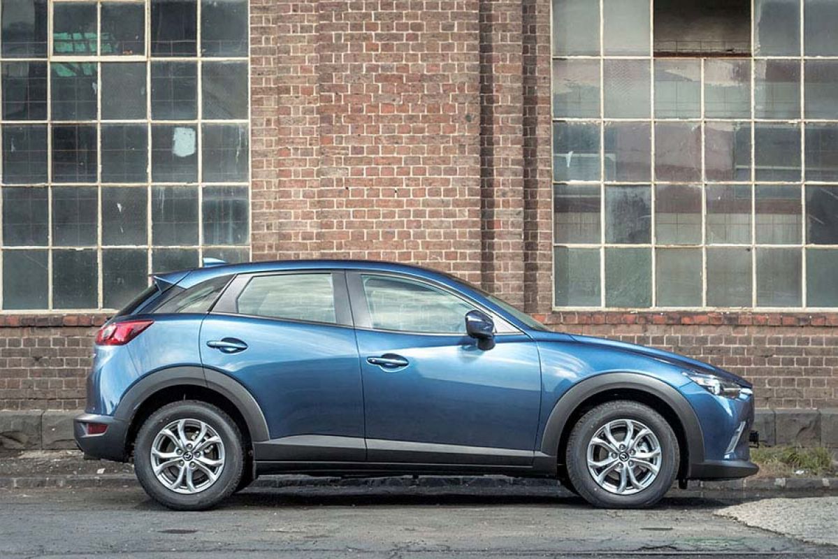 blue mazda cx 3 parked next to brick wall