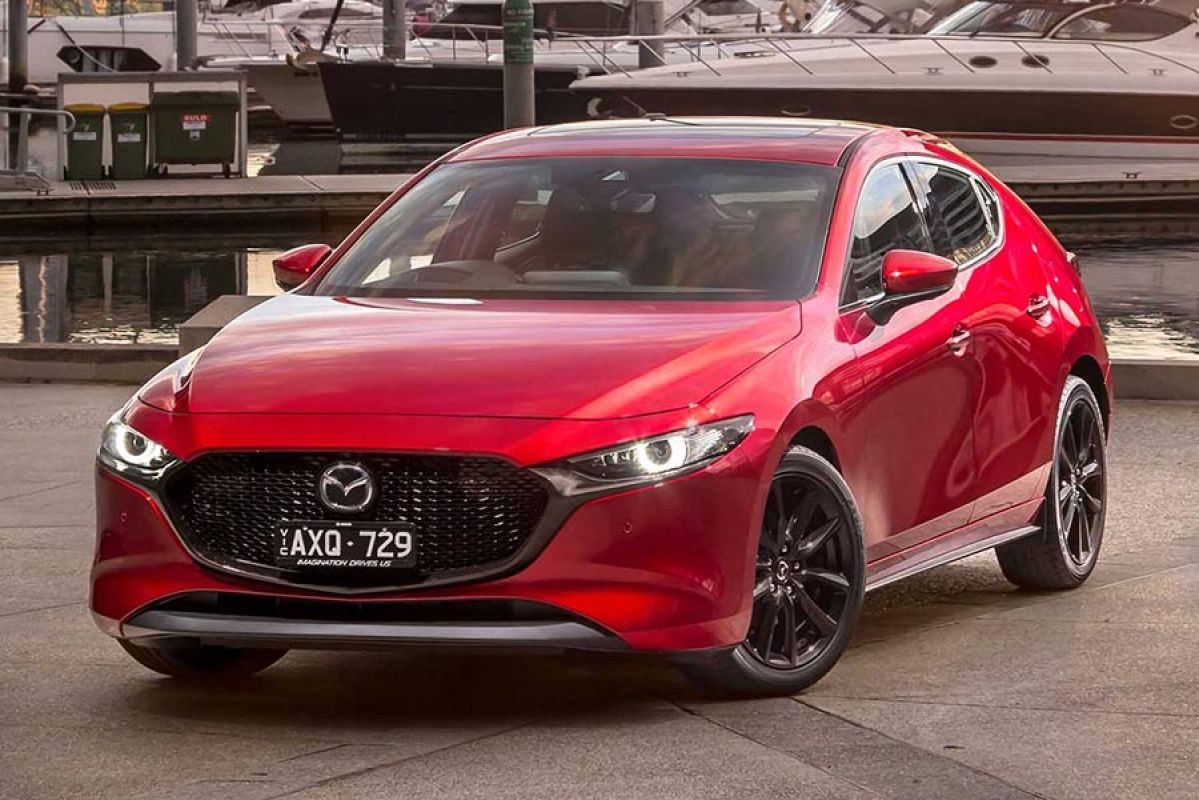 red mazda 3 parked on concrete wharf next to boats and water