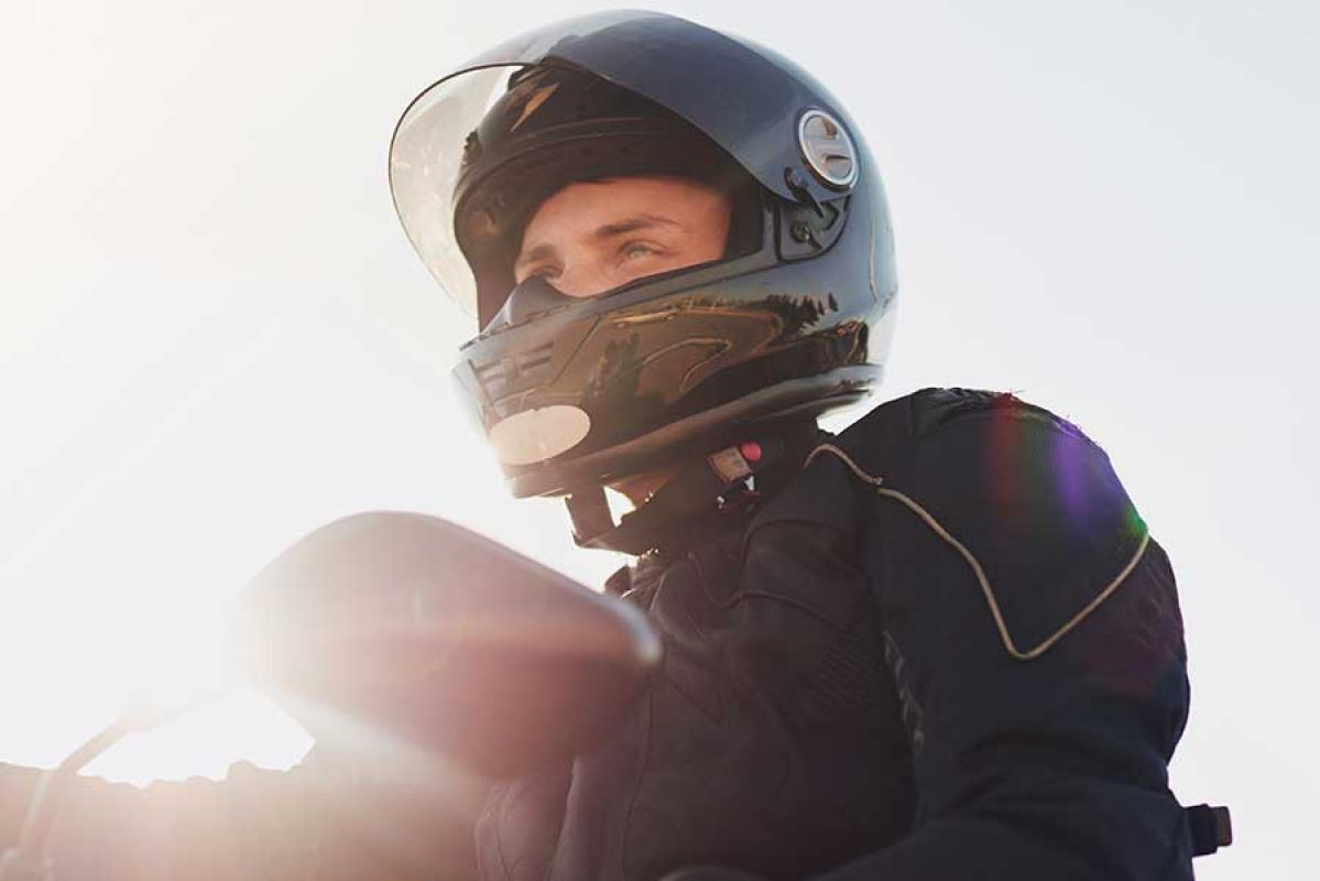 Man rides motorbike with safety gear and helmet.